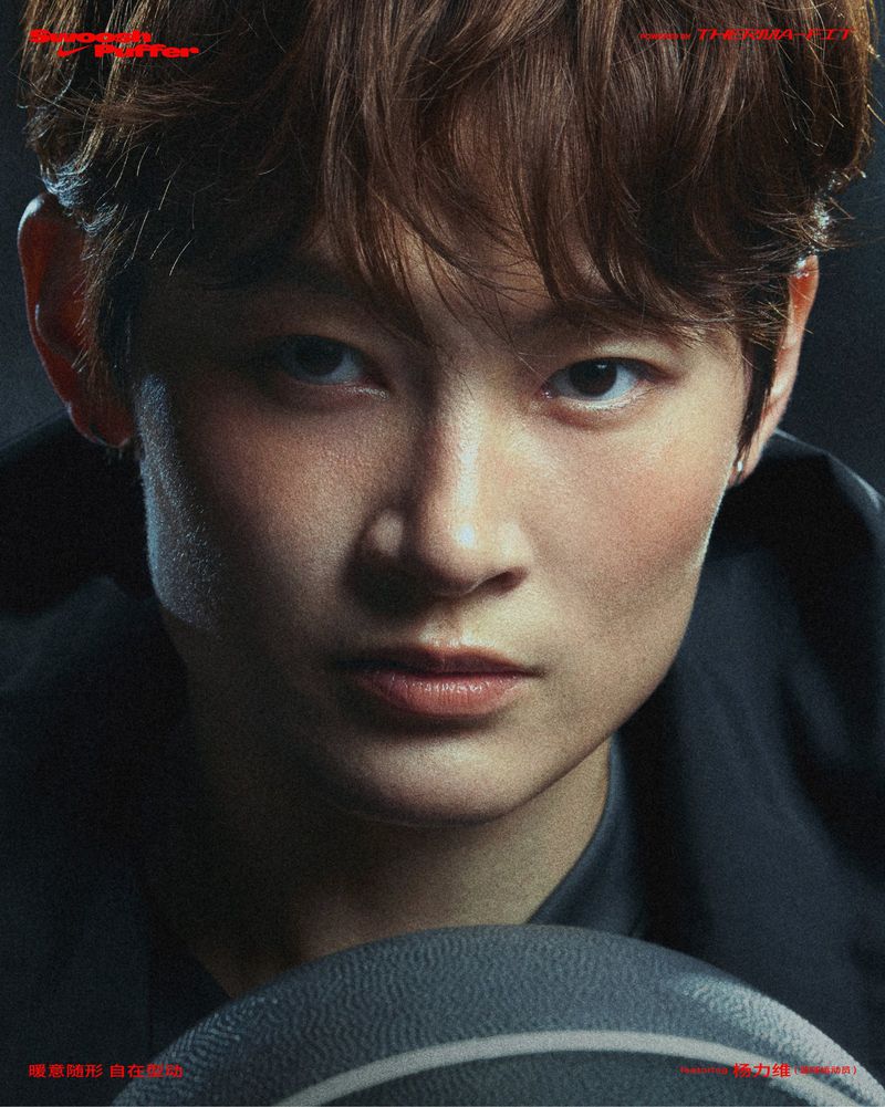 Close-up portrait of a young adult with dark hair and basketball, focusing on facial features and dramatic lighting in a dark setting.