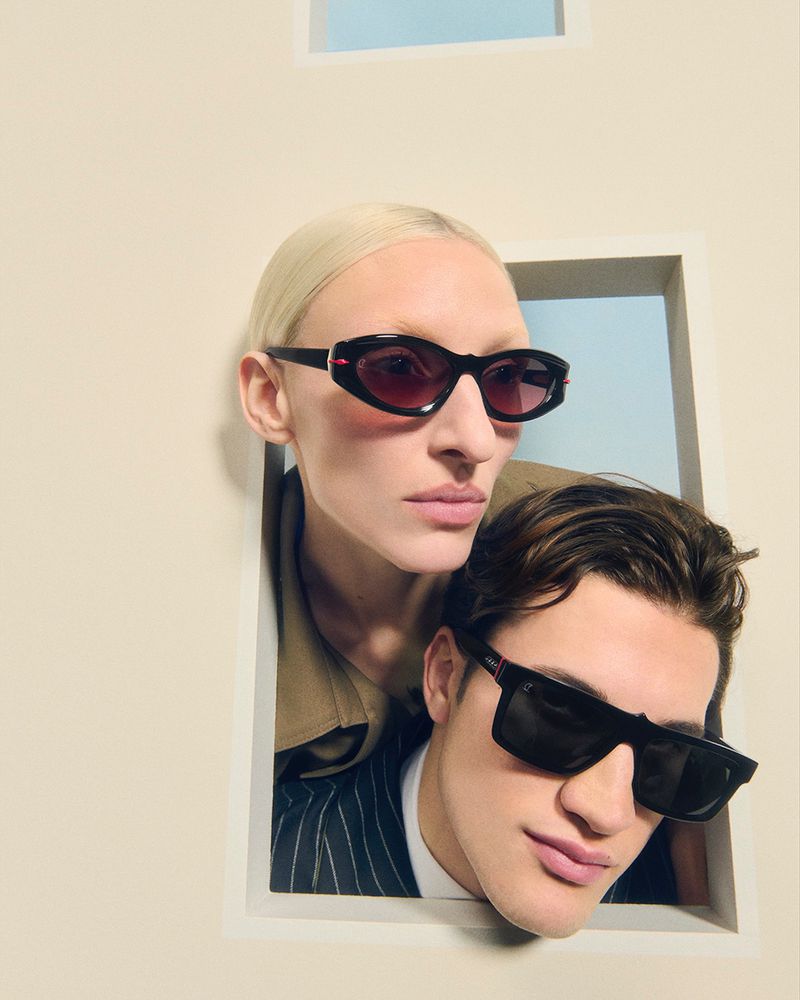 Portrait of a stylish adult male and female in sunglasses, posing together within a white wall frame, fashion, and beauty.