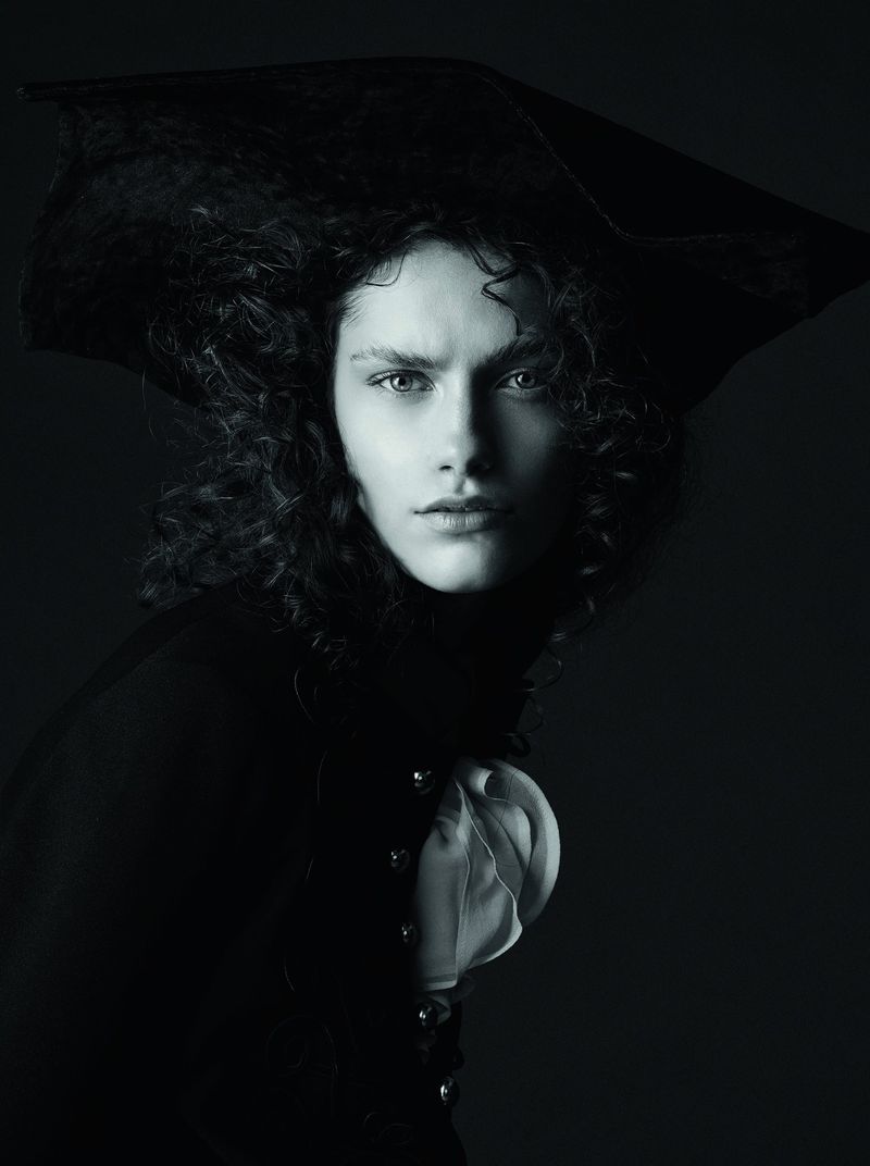 Dramatic black and white portrait of a person wearing a tricorn hat and ruffled shirt against a dark background in a photo studio.
