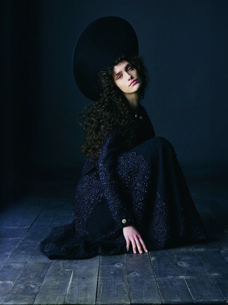 Model Julia Kuźniar kneeling in a dark tweed coat and large round hat for Telva magazine