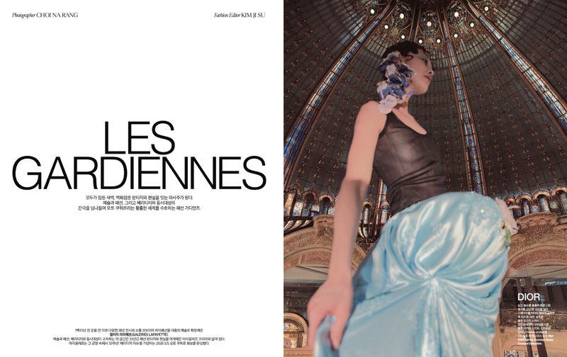 Fashion editorial shot of an Asian female model in a black top and light blue satin skirt, posing inside an ornate domed building.