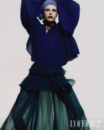 Model in blue blouse and tiered skirt wearing a matching headwrap against a plain white background for L'Officiel Hong Kong.