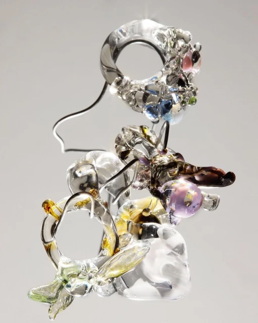 Abstract arrangement of decorative glass objects with transparent qualities, featuring spheres and rings against a neutral background.