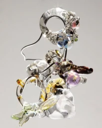 Close-up of sculptural glass rings and organic glass art pieces suspended against a smooth grey gradient background.