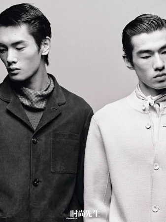 Monochrome studio shot of two Asian male fashion models in jackets and turtlenecks, showcasing modern menswear style with minimalist backdrop.