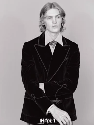 Monochrome portrait of a male model wearing a dark velvet blazer with contrast piping against a plain light background