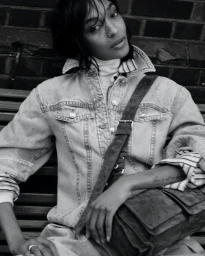 Model Jourdan Dunn in denim jacket and striped top seated on a park bench for British Vogue Seize The Day project