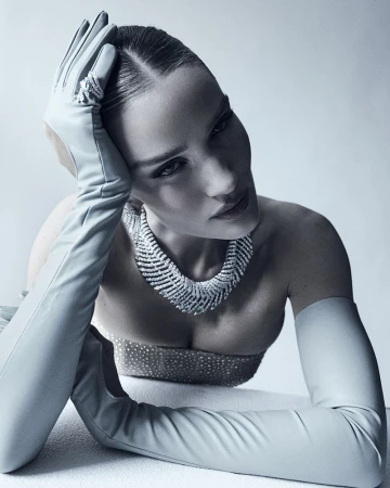 Elegant woman in gloves and diamond necklace. Posing fashion beauty shot with clean studio lighting and soft color palette. 