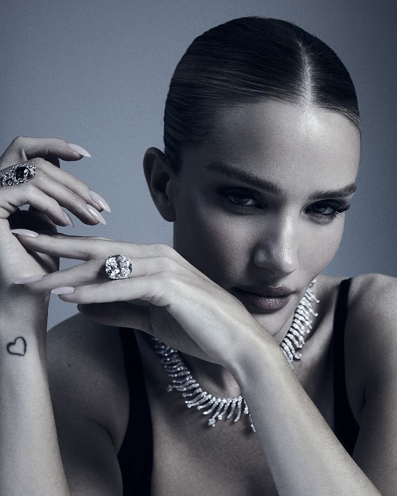 Close-up portrait of a woman wearing diamond jewelry and a black top against a grey background, showcasing beauty and high-fashion elegance.