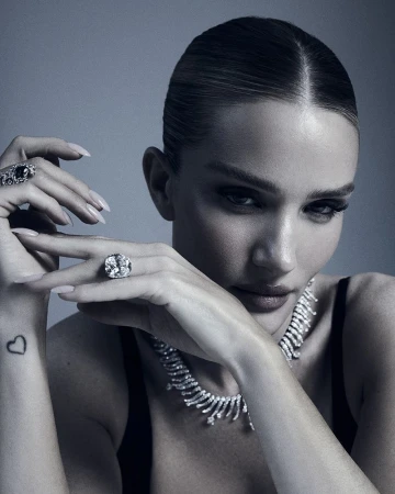 Close-up portrait of a woman wearing diamond jewelry and a black top against a grey background, showcasing beauty and high-fashion elegance.