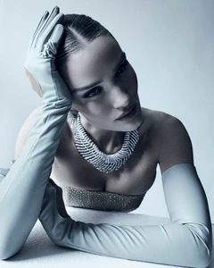 Model Rosie Huntington Whiteley wearing diamond necklace and long leather gloves against a plain white background