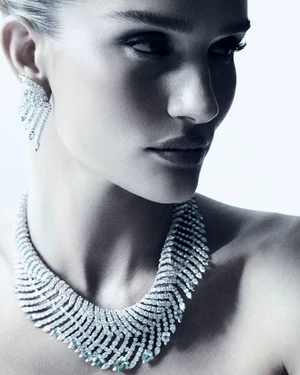 Close-up portrait of model Rosie Huntington-Whiteley wearing a diamond necklace and earrings against a white background