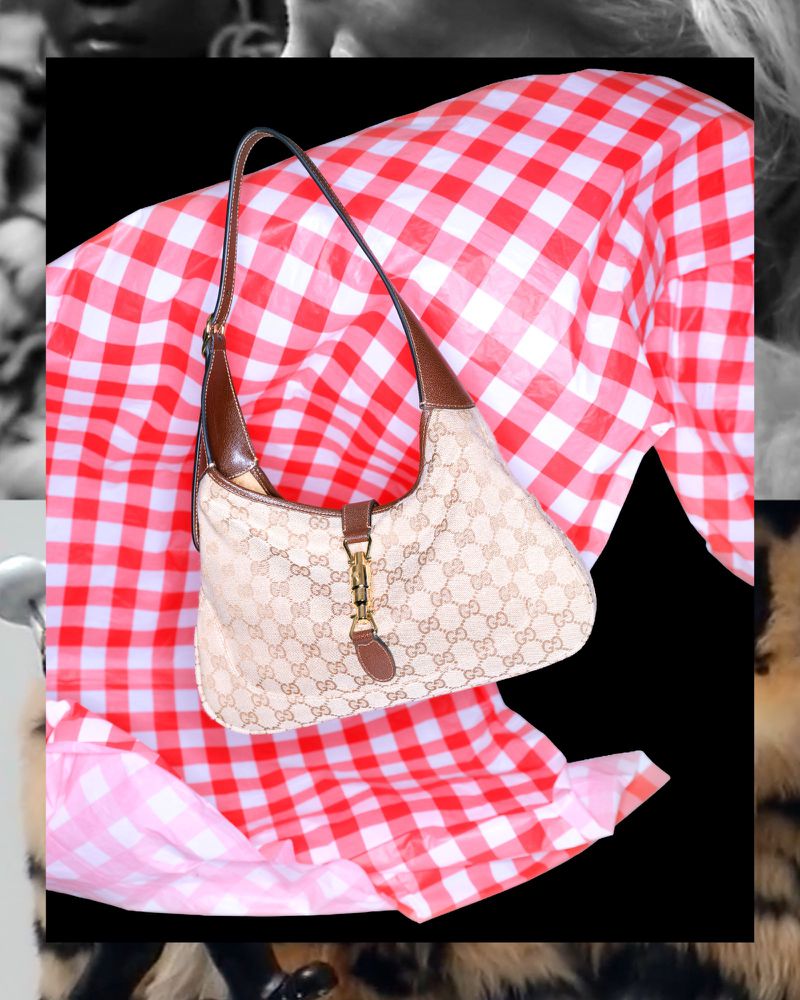 Gucci handbag with G monogram pattern and brown leather trim displayed on red and white checkered textile against a black backdrop.