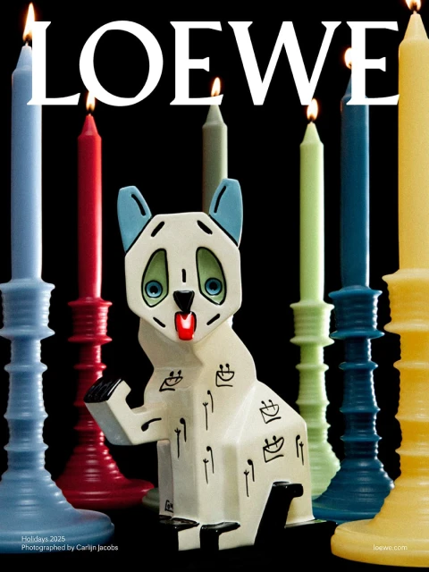 Loewe holiday 2025 campaign features a sculptural ceramic animal figure surrounded by colorful taper candles on a black background.