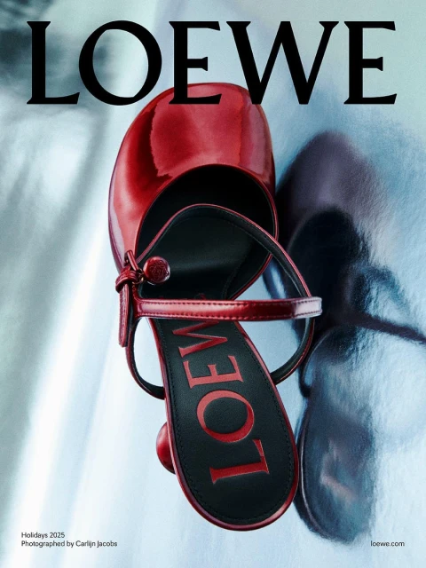 Close-up of a red patent leather heeled sandal by Loewe, displayed on a silvery, shimmering surface, advertising Loewe Holidays 2023.
