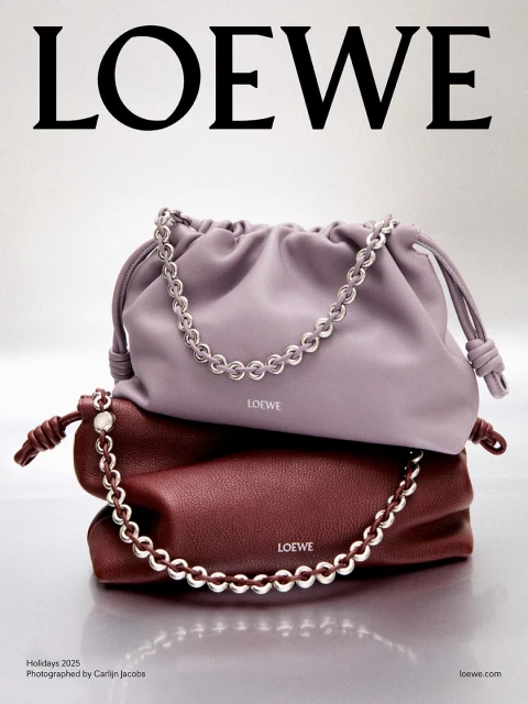 Advertisement for LOEWE showcasing two leather handbags stacked. Each bag is draped with a silver-tone chain. The handbags are lavender and burgundy.
