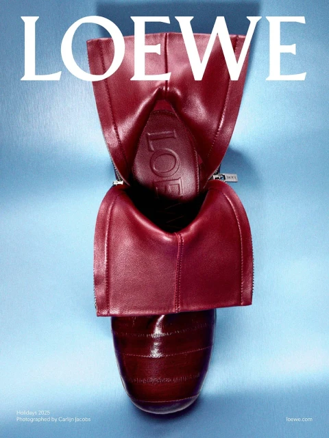 High-angle studio shot of a shiny, dark red leather Loewe shoe, showcasing its unique, deconstructed design and craftsmanship against a blue background.