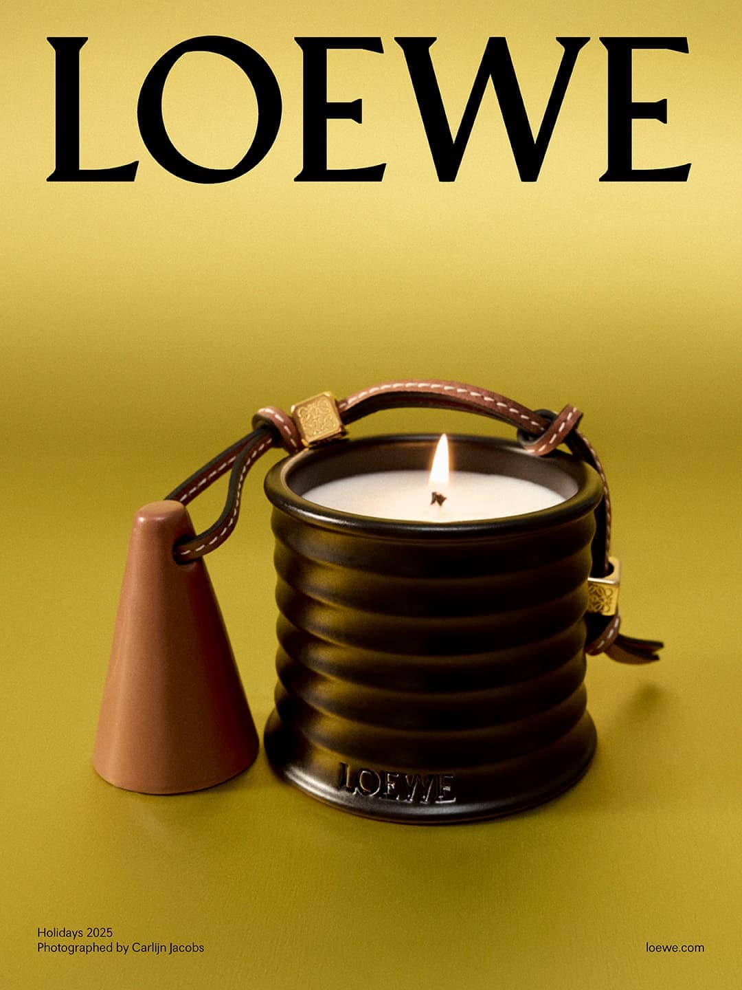 Loewe candle in a black ribbed container with brown leather handle and bell, set against a light yellow background with Loewe logo.