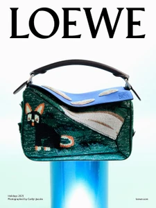 Loewe leather handbag featuring embroidered animal graphics resting on a glowing blue cylindrical pedestal against a gradient background.