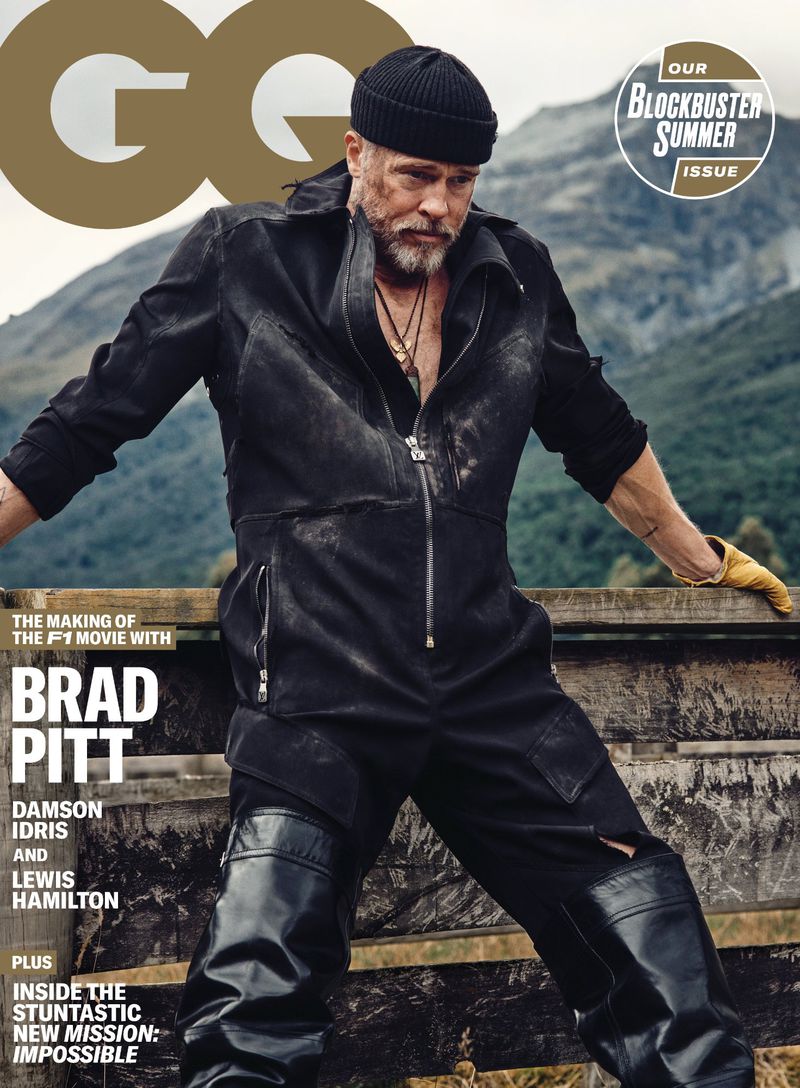 Brad Pitt on GQ magazine cover, wearing a black jumpsuit and beanie, set against a mountain backdrop. He is posing with arms spread on a wooden beam.