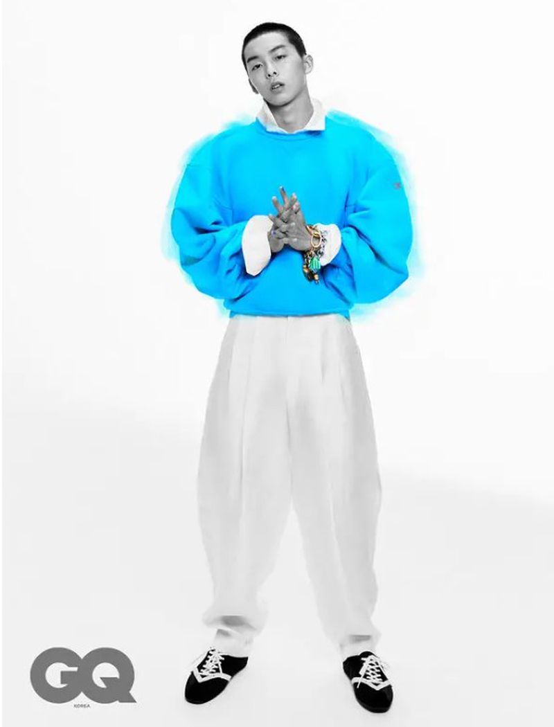 Full shot of a male model in a bright blue sweatshirt and white pants, posed against a white backdrop. Fashion editorial, GQ Korea.