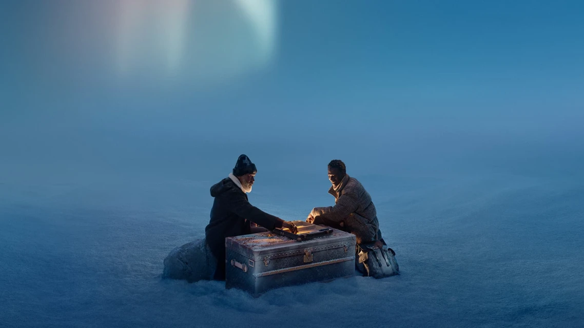 Two men sit in a snowy landscape beside a trunk with glowing edges. One man is older with a beard, and the other is younger.