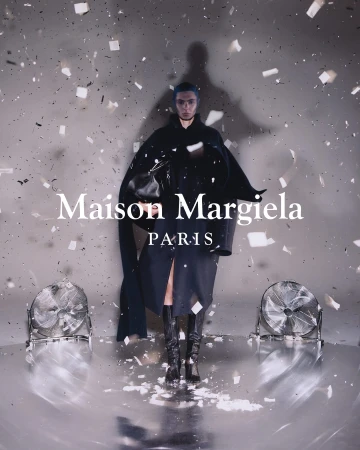 A fashion shot of a person in dark clothing standing amid confetti on a reflective floor, flanked by two fans, and logo text overlay.