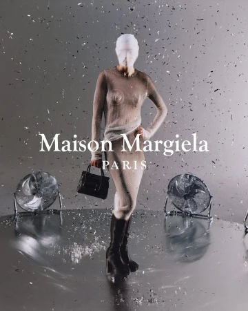 Fashion shot of a model in a sheer dress and boots, holding a handbag, with stage fans and falling confetti against a grey backdrop.