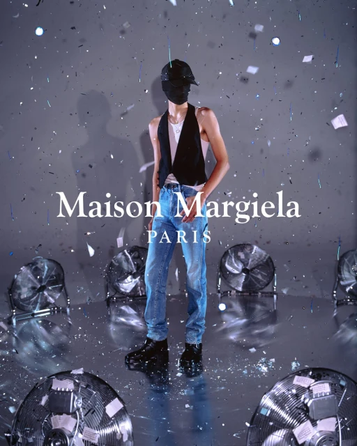 Fashion shoot: A person poses in jeans and a vest, mask over face, surrounded by vintage fans and confetti in a silver studio.