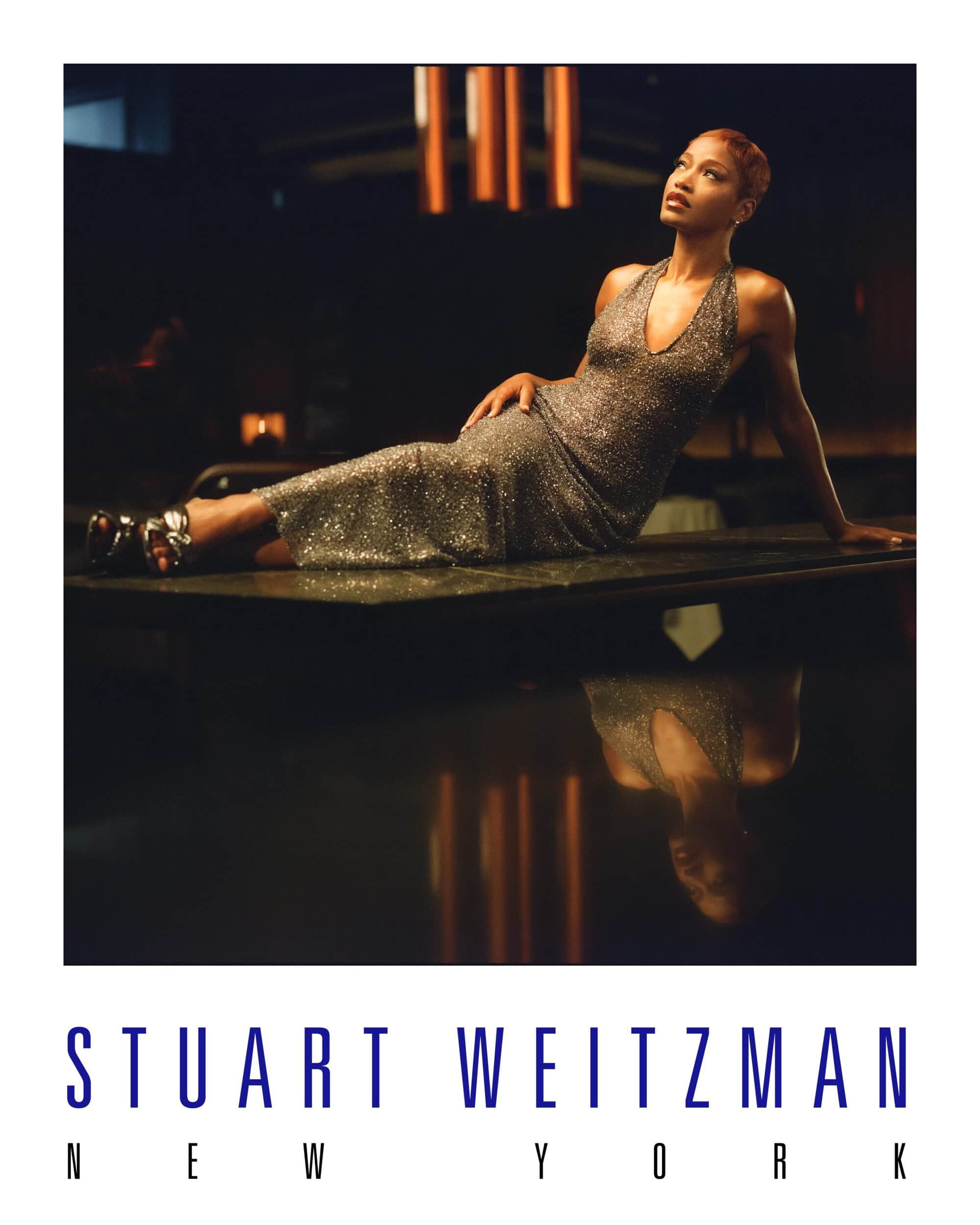 A fashion shot features an adult female model reclining in a sparkling gown, looking up in a dimly lit indoor environment. 