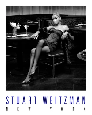 Keke Palmer seated in a restaurant wearing a strapless corset and metallic heels for Stuart Weitzman holiday ad campaign