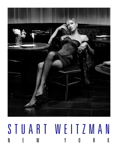 Keke Palmer seated in a booth wearing a strapless corset and sparkling heels for Stuart Weitzman Holiday 2025 campaign.