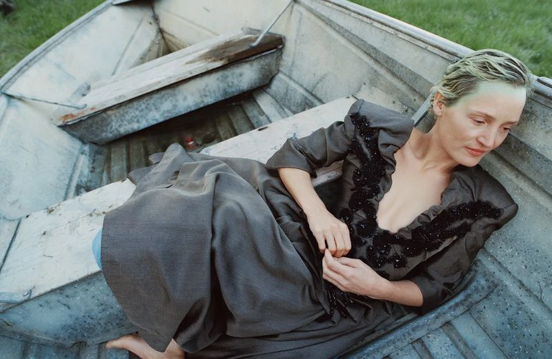 Vicky Krieps lying in a metallic boat wearing a dark grey embellished dress with beaded details for AnOther Magazine.