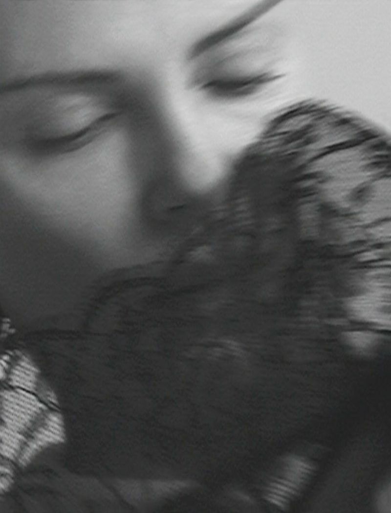 Monochrome close-up of a woman with eyes closed, partially veiled by black lace, creating an intimate and sensual black and white image.