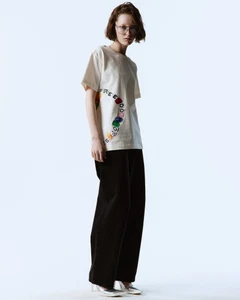 Model in printed t-shirt and black trousers posing against a bright white background for Freedom of Space lookbook