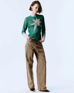 Model in green long-sleeve mesh top and brown baggy jeans against a white seamless background for Freedom Of Space project.