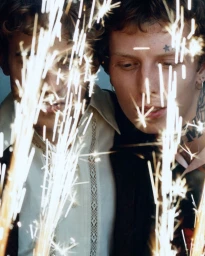 Two men posing together with bright sparkling lights obscuring parts of the foreground in an editorial portrait for Vogue Polska.