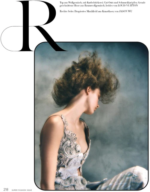 A woman with voluminous hair wears a sculpted white dress in a studio setting, bathed in soft, diffused light, for a fashion editorial.