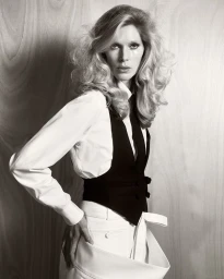 Model Iselin Steiro in a white shirt and black waistcoat against a wooden background for D Repubblica