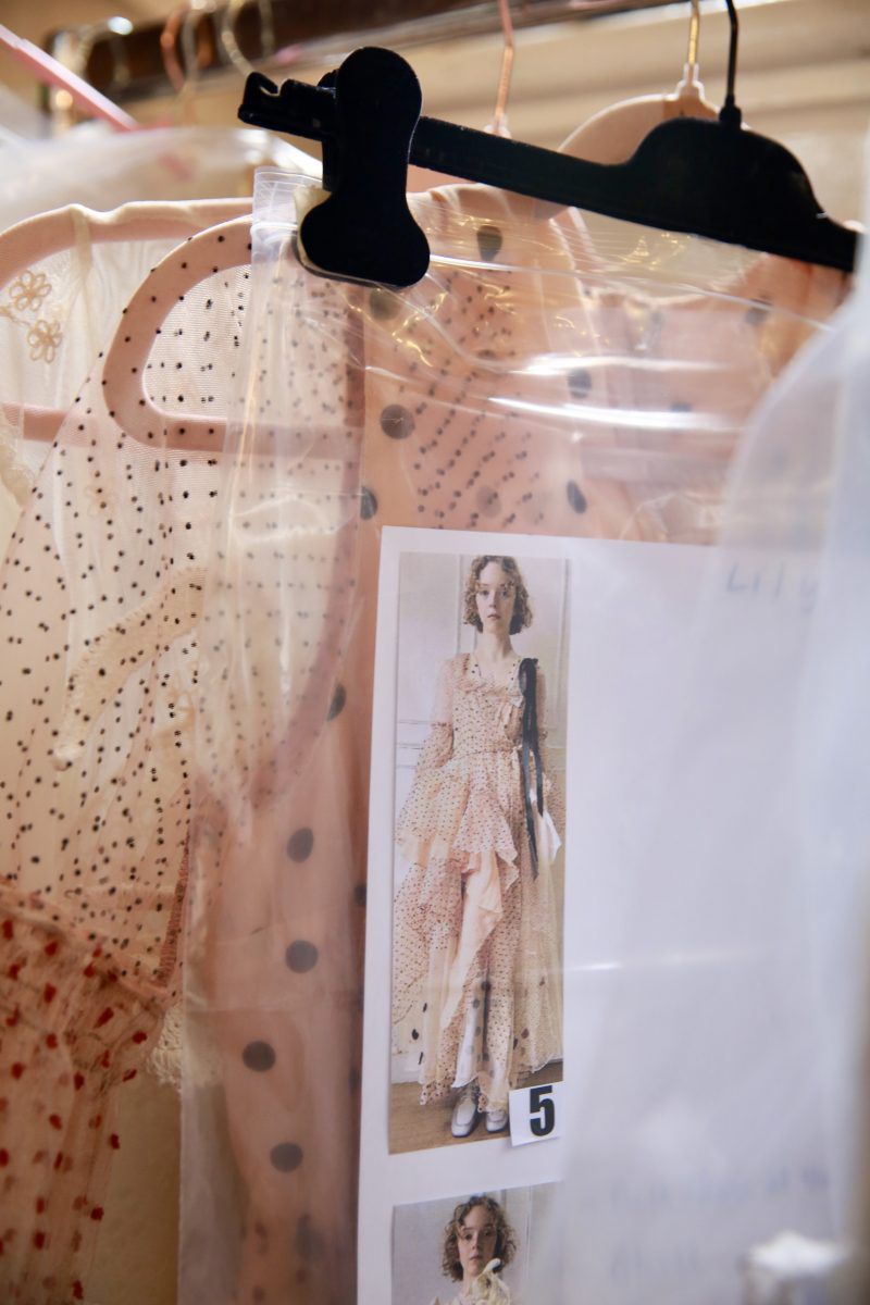 Clothing rack with a polka-dot dress and a fashion photograph pinned to plastic with a model wearing a similar polka-dot dress.