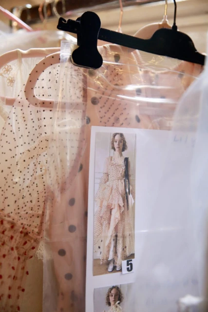Clothing rack with a polka-dot dress and a fashion photograph pinned to plastic with a model wearing a similar polka-dot dress.