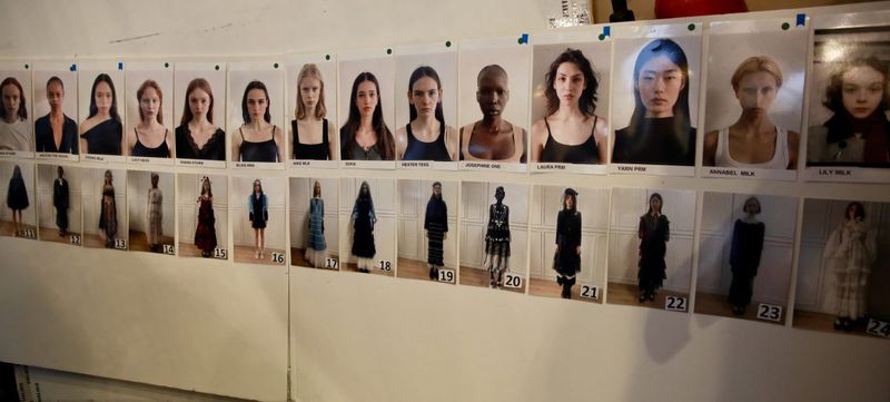 Row of diverse fashion models' headshots and full-body photos on a wall, used for casting or selection purposes, showcasing different looks.