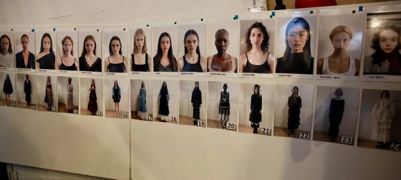 Row of diverse fashion models' headshots and full-body photos on a wall, used for casting or selection purposes, showcasing different looks.