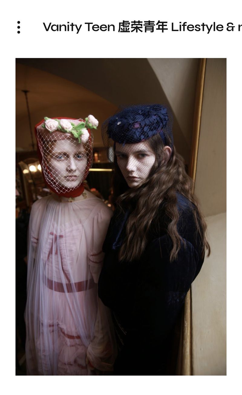 Two models pose in vintage-inspired fashion featuring headpieces with netting and floral accents. The image has an editorial feel.