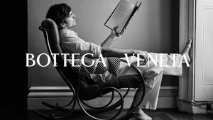 Jacob Elordi seated in a rocking chair reading a book for Bottega Veneta Fall 2025 ad campaign, shot in black and white.