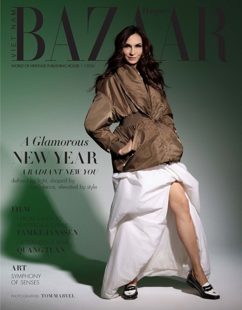 Fashion magazine cover features a brunette woman wearing a bomber jacket and white dress, posing in front of a green background.