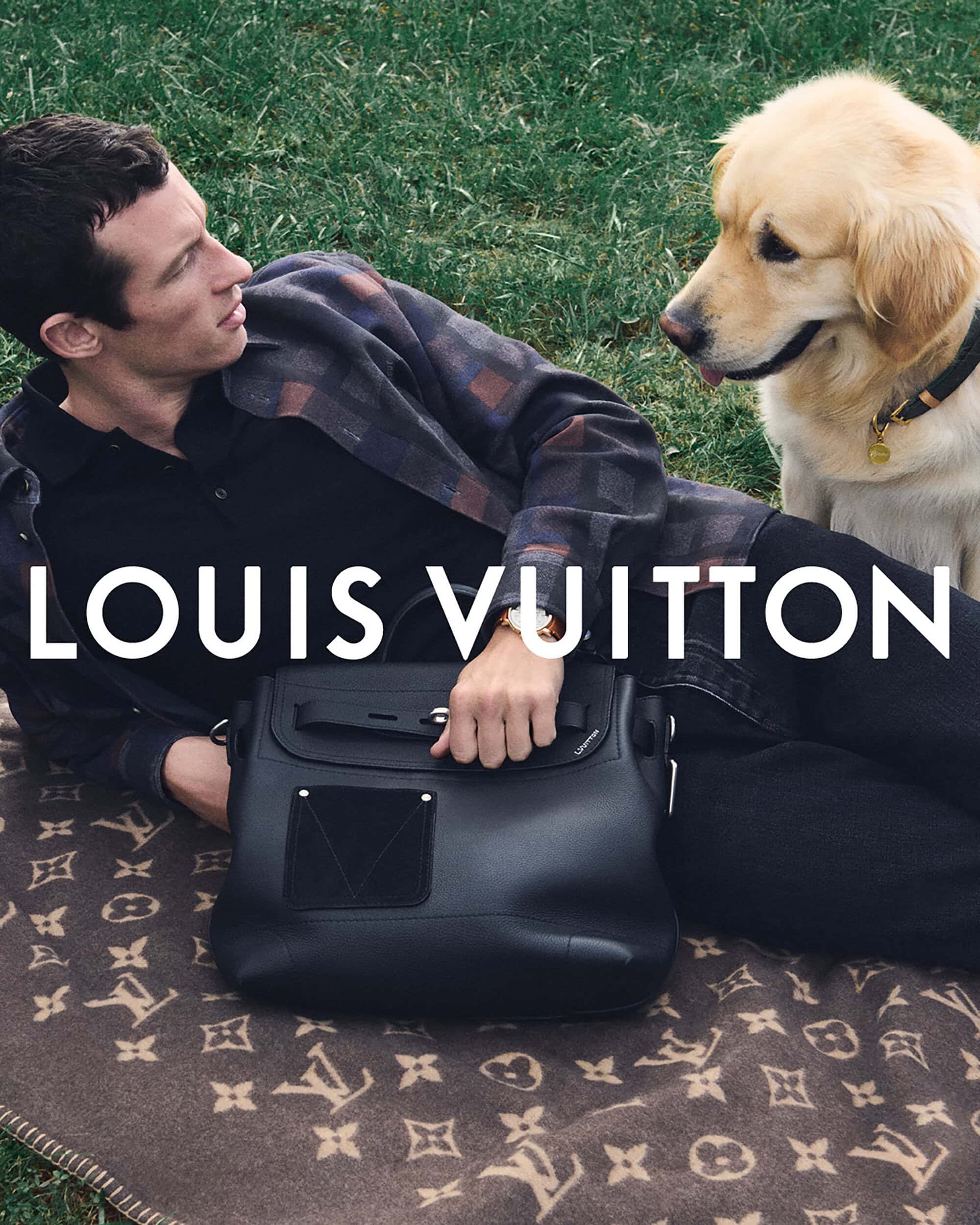 A man poses with a dog next to a black leather satchel and monogram blanket, featuring the Louis Vuitton brand logo in an outdoor setting.