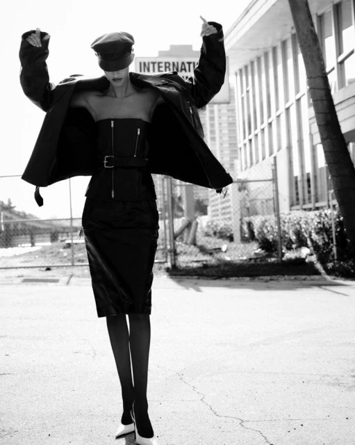 A striking black and white fashion shot features a woman in a stylish outfit, posing against an urban backdrop with a building and palm tree.