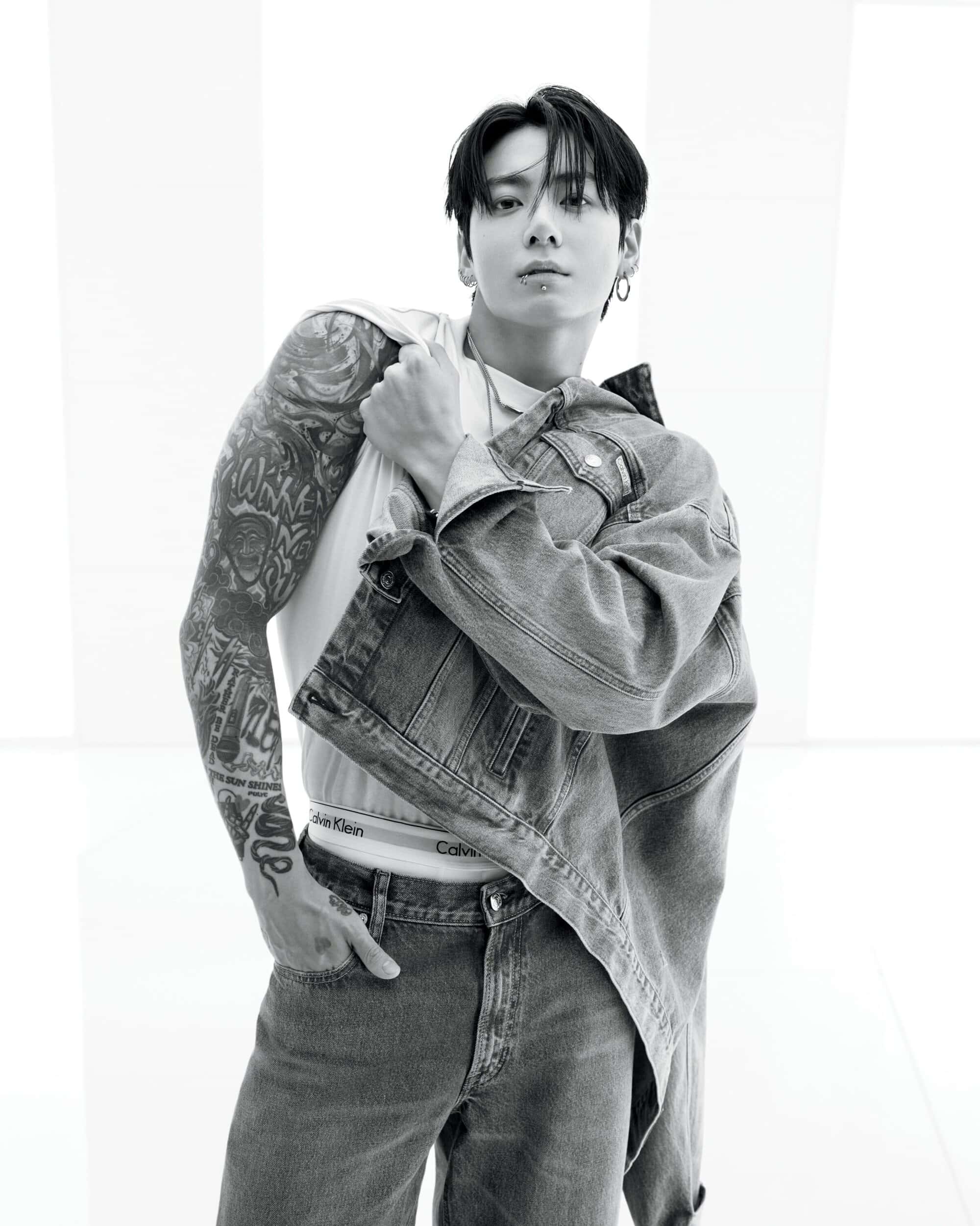 Jung Kook in a black and white fashion portrait wearing a denim jacket and white tank top for Calvin Klein