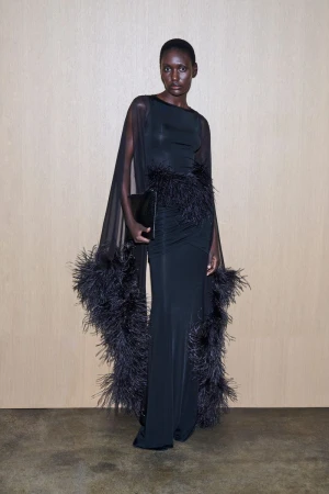 Elegant African woman in a black gown with feather detailing, holding a clutch, posing in a minimalist studio setting, high-fashion editorial.